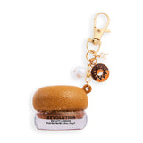 Revolution Sparkly Lip & Cheek Jelly in a golden pot with sweet charm keychain, ideal for on-the-go shimmer.