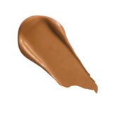 Revolution Conceal and Define Full Coverage Concealer swatch in a warm brown tone on white background