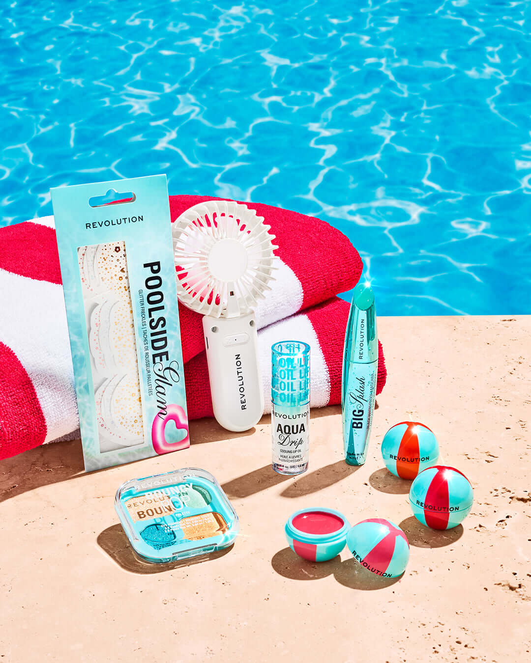 Revolution Poolside Hand Held Electric Fan White with poolside essentials including snacks and beauty products.